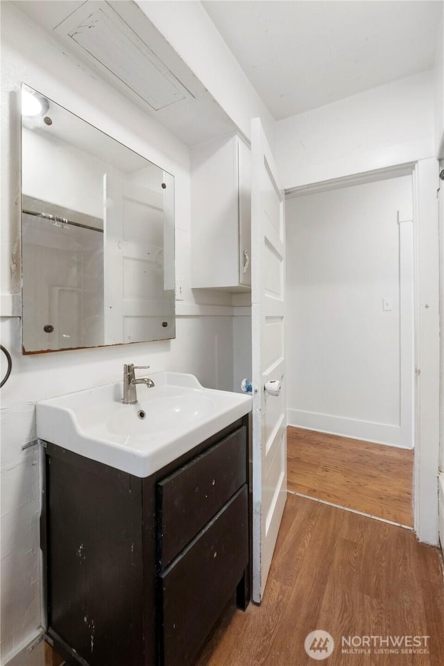 bathroom with vanity, wood finished floors, and baseboards