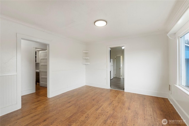 spare room with a wainscoted wall, crown molding, and wood finished floors