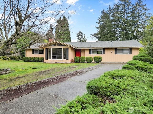 single story home featuring driveway, a chimney, and a front yard