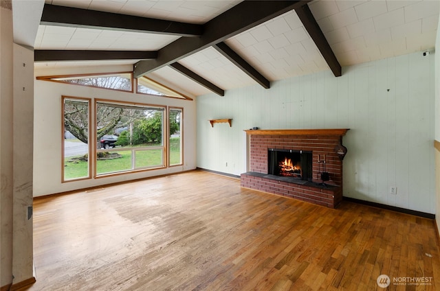 unfurnished living room with visible vents, a brick fireplace, baseboards, lofted ceiling with beams, and wood finished floors