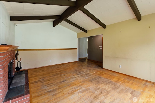 unfurnished living room featuring a fireplace, vaulted ceiling with beams, baseboards, and wood finished floors