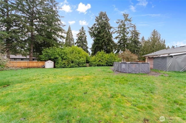 view of yard featuring an outdoor pool, a storage shed, an outdoor structure, and fence