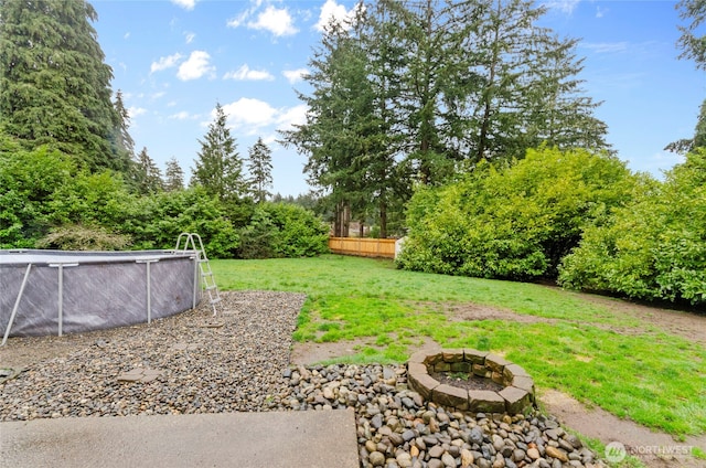 view of yard with an outdoor pool, an outdoor fire pit, and fence