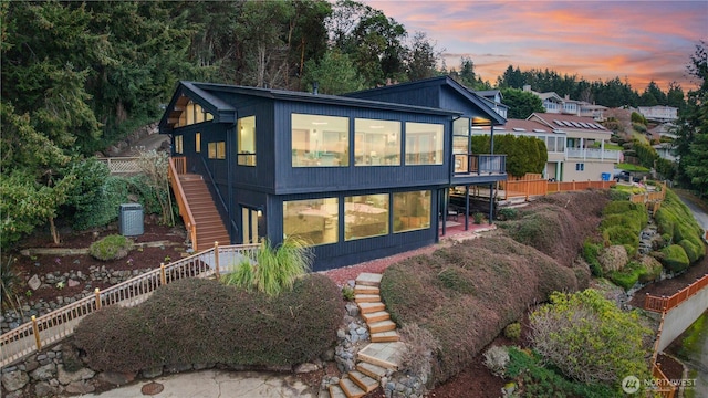 back of property with stairway, fence, and a sunroom