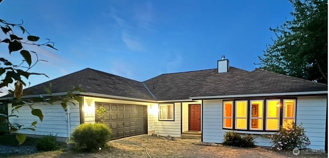 rear view of house featuring roof with shingles, a chimney, entry steps, a garage, and driveway