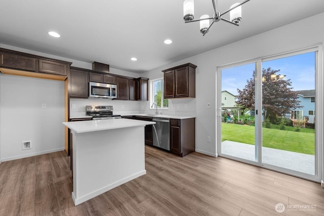 kitchen with dark brown cabinets, light countertops, stainless steel appliances, and light wood-style flooring