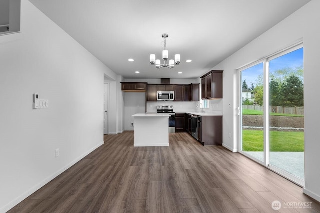 kitchen featuring a notable chandelier, dark brown cabinets, dark wood finished floors, a sink, and stainless steel appliances