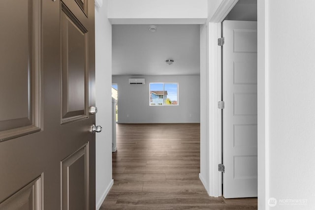 hallway with a wall unit AC, baseboards, and dark wood-type flooring