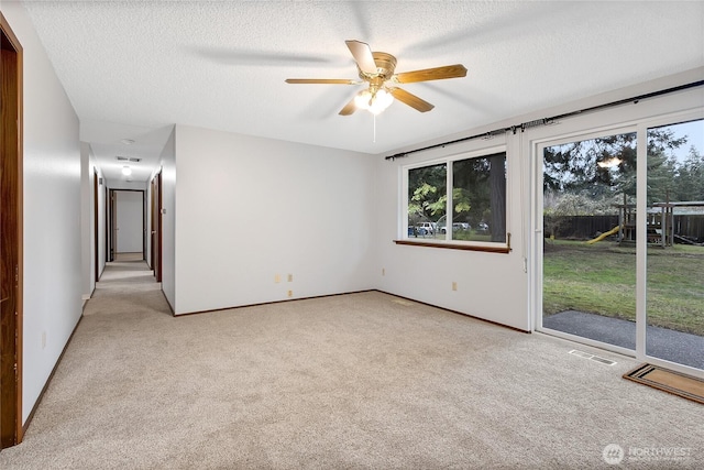 spare room with light carpet, ceiling fan, visible vents, and a textured ceiling