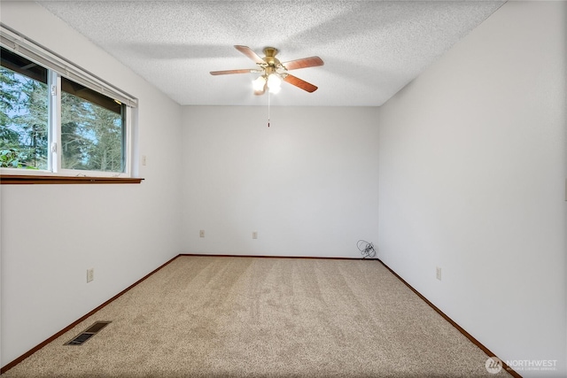 carpeted empty room featuring a ceiling fan, baseboards, visible vents, and a textured ceiling