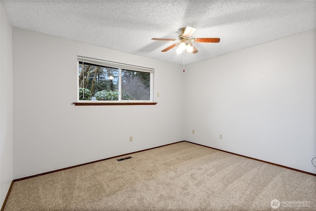 carpeted empty room with ceiling fan, a textured ceiling, visible vents, and baseboards