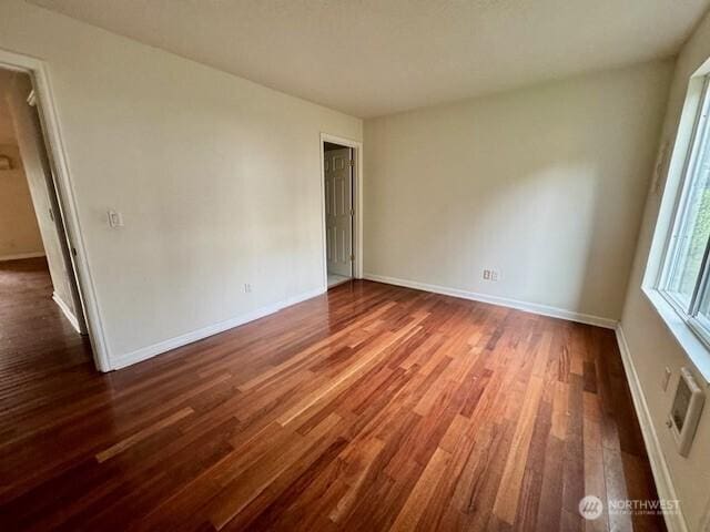 unfurnished room featuring baseboards and dark wood finished floors