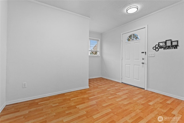 foyer with light wood-style flooring, a textured ceiling, baseboards, and crown molding