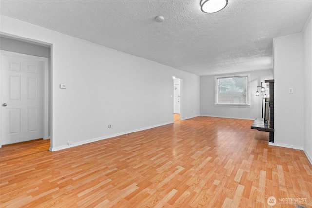 unfurnished living room featuring light wood-style flooring, baseboards, and a textured ceiling