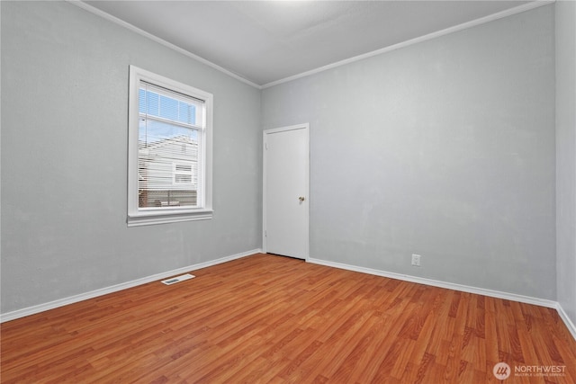 spare room featuring baseboards, light wood-style flooring, visible vents, and crown molding