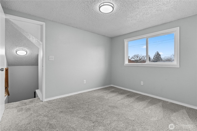 carpeted empty room featuring a textured ceiling and baseboards