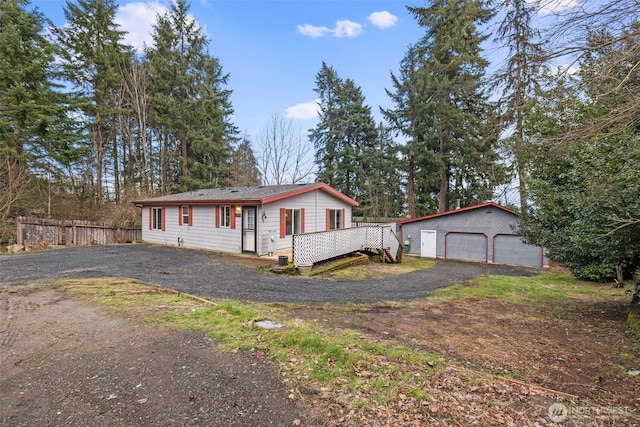 view of front of home with a detached garage, fence, and an outbuilding