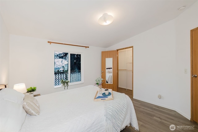 bedroom with baseboards, vaulted ceiling, and wood finished floors