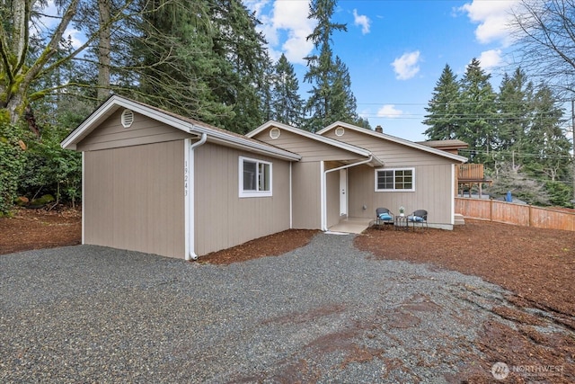 ranch-style house with gravel driveway and fence