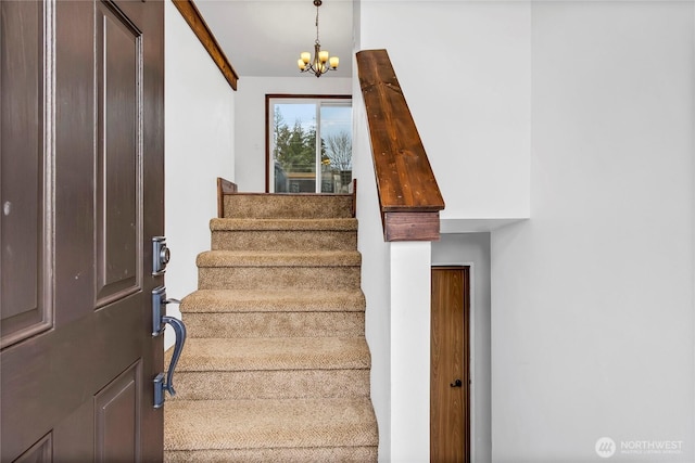 stairway featuring a notable chandelier