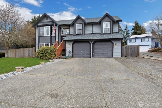 view of front of home with an attached garage, fence, driveway, roof with shingles, and a front lawn