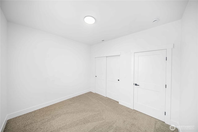 unfurnished bedroom with a closet, carpet, and baseboards