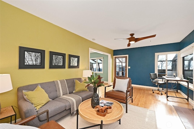 living room featuring ceiling fan, light wood-style flooring, and baseboards