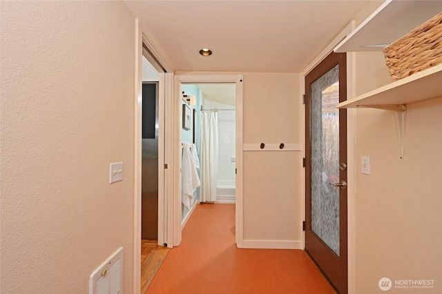 hallway featuring a textured wall and visible vents