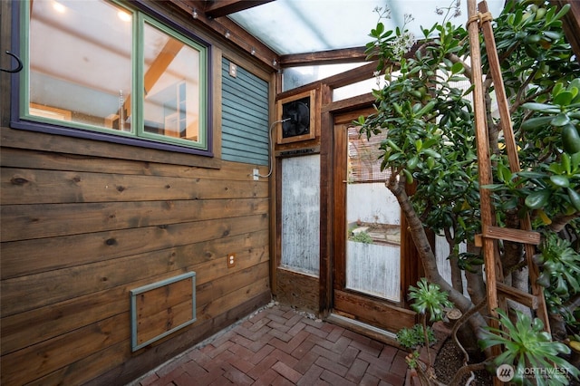 exterior space with wood walls and brick floor