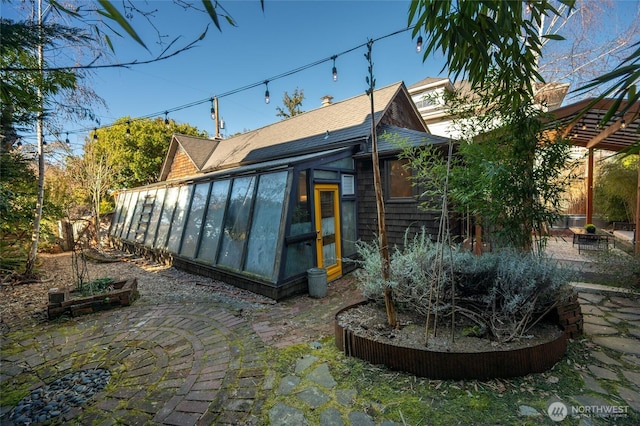 back of property with a sunroom, roof with shingles, a patio, and a pergola