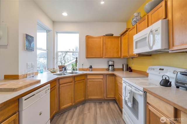 kitchen with white appliances, light countertops, and a sink