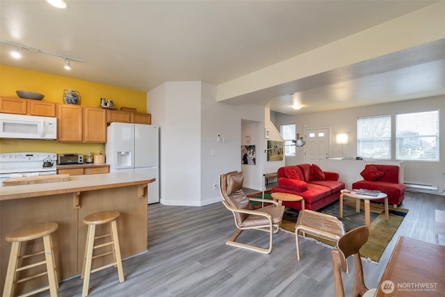 kitchen featuring white appliances, light countertops, light wood-style flooring, and open floor plan