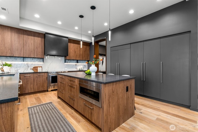 kitchen with modern cabinets, a center island, hanging light fixtures, stainless steel range with electric cooktop, and exhaust hood