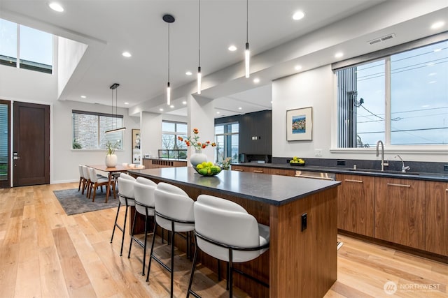 kitchen with a kitchen bar, decorative light fixtures, a kitchen island, and a sink