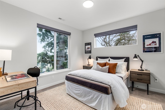 carpeted bedroom featuring baseboards, multiple windows, and visible vents