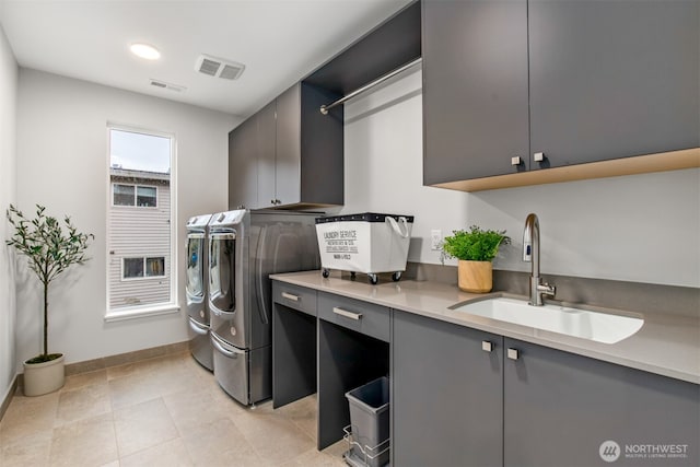 laundry room with a sink, visible vents, baseboards, cabinet space, and washing machine and clothes dryer