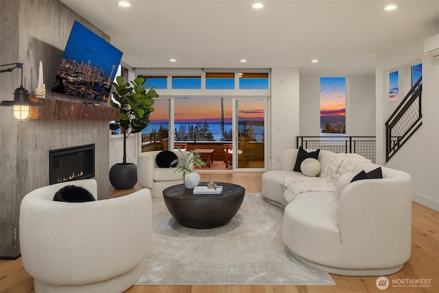 living area with floor to ceiling windows, a glass covered fireplace, recessed lighting, and wood finished floors