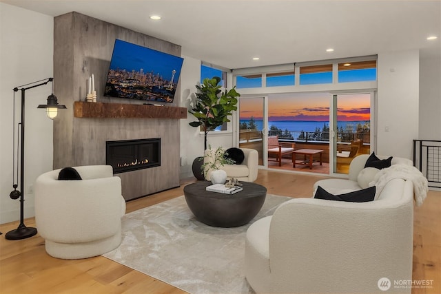 living room with a wall of windows, recessed lighting, wood finished floors, and a large fireplace