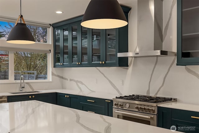 kitchen featuring glass insert cabinets, high end stainless steel range, wall chimney range hood, and a sink