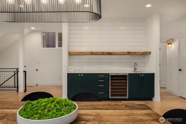 bar featuring wine cooler, light wood-type flooring, recessed lighting, wet bar, and a sink