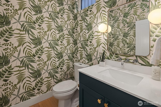 half bath with wallpapered walls, toilet, and vanity