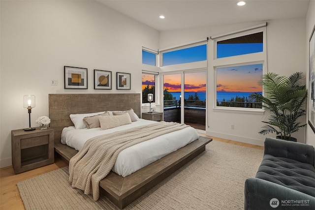 bedroom with a water view, access to outside, recessed lighting, light wood finished floors, and baseboards