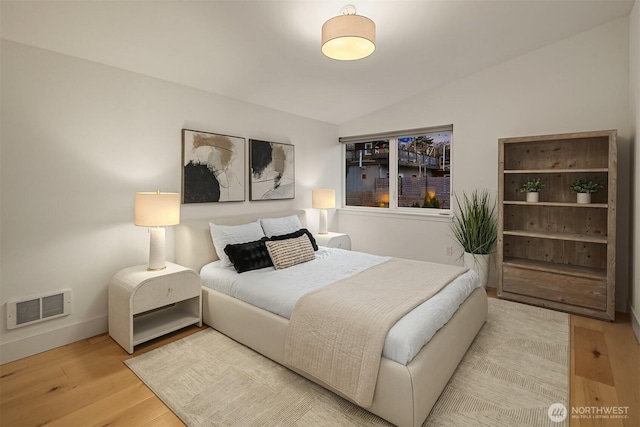 bedroom with visible vents, baseboards, lofted ceiling, and wood finished floors