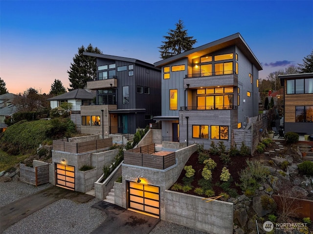 contemporary home featuring a garden, a garage, board and batten siding, and driveway