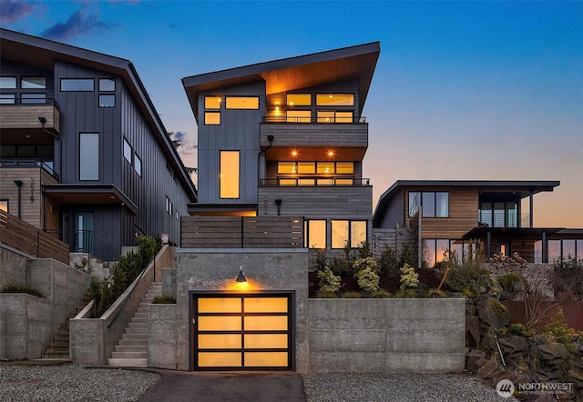 view of front of home with stairway, an attached garage, driveway, and board and batten siding