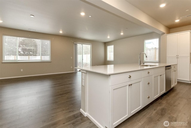 kitchen with a center island with sink, white cabinetry, light countertops, and a sink