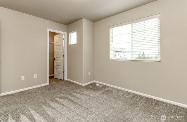 carpeted spare room with visible vents and baseboards