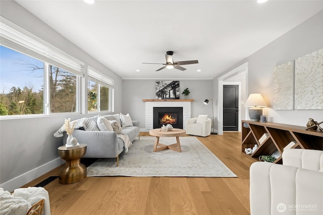 living room with baseboards, light wood-style flooring, ceiling fan, a fireplace, and recessed lighting