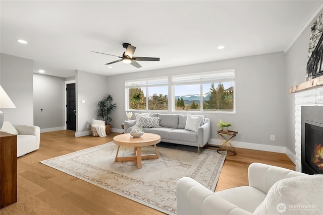 living room with recessed lighting, a brick fireplace, baseboards, and wood finished floors