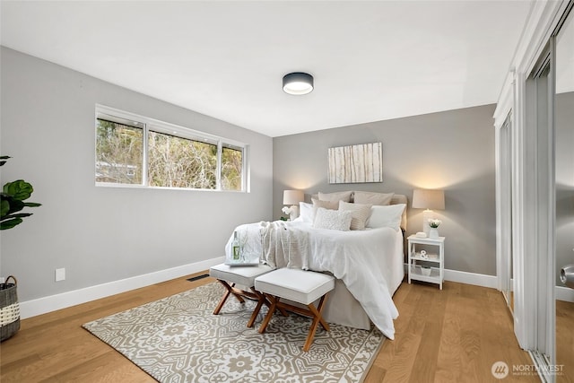 bedroom with wood finished floors, visible vents, and baseboards